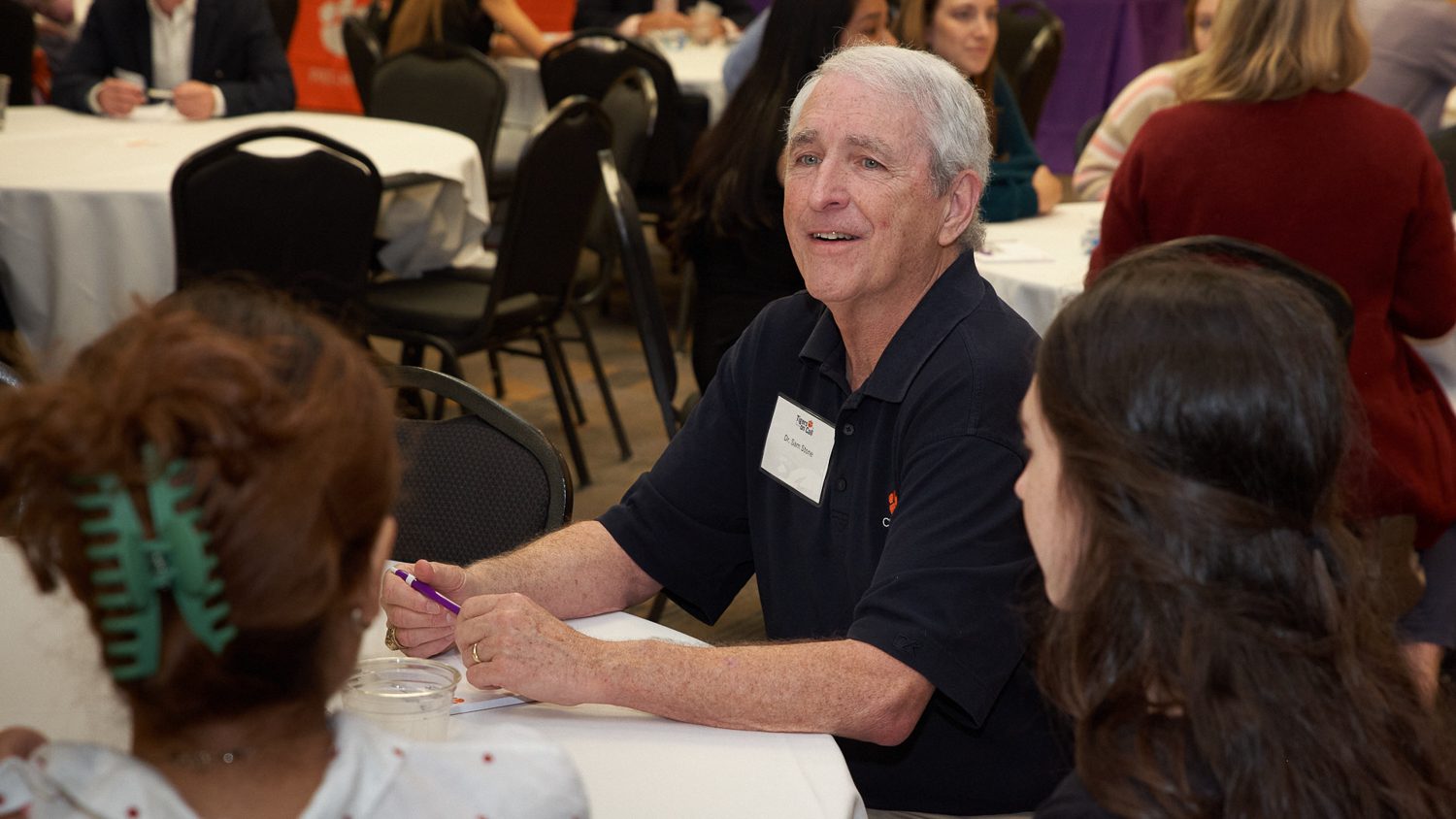 A man (Dr. Sam Stone) sitting at a table talks to students at a Tigers on Call event.