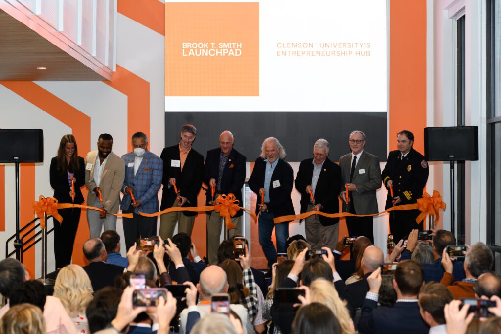Clemson leaders cut a large orange ribbon in front of a screen that reads "Brook T. Smith Launchpad Clemson University's Entrepreneurship Hub"