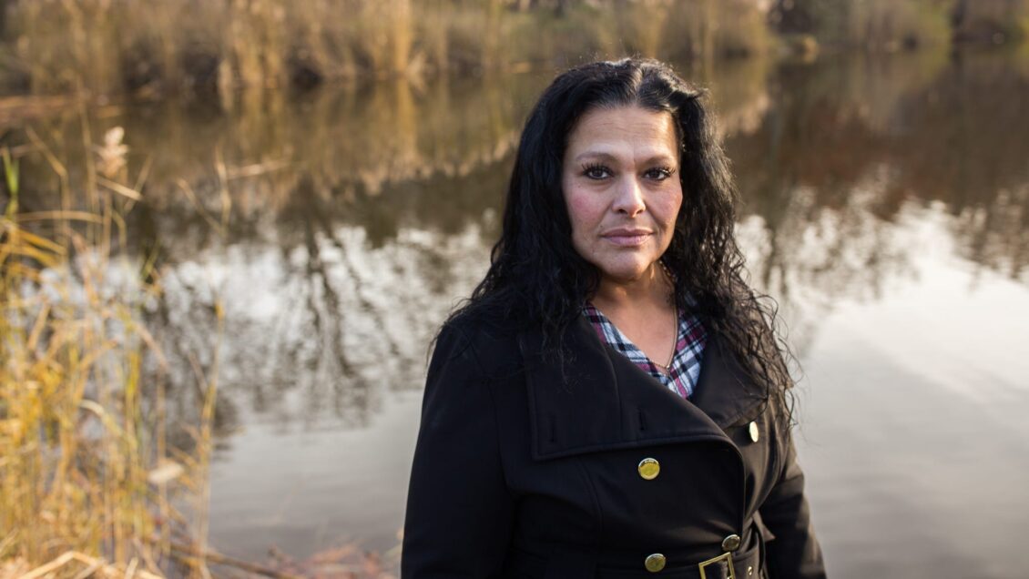 Domestic violence survivor Kim Dadou Brown stands in front of a pond on a fall morning.
