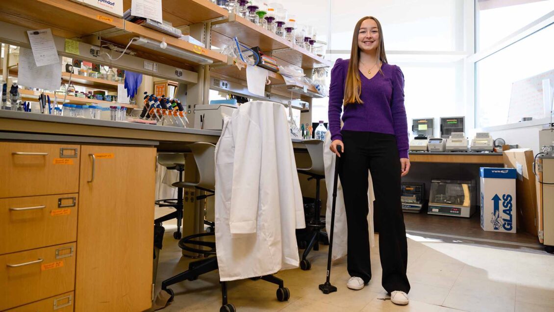 National Scholar and genetics major Elizabeth Caldwell standing, supported by her cane, in a lab on Clemson University campus.