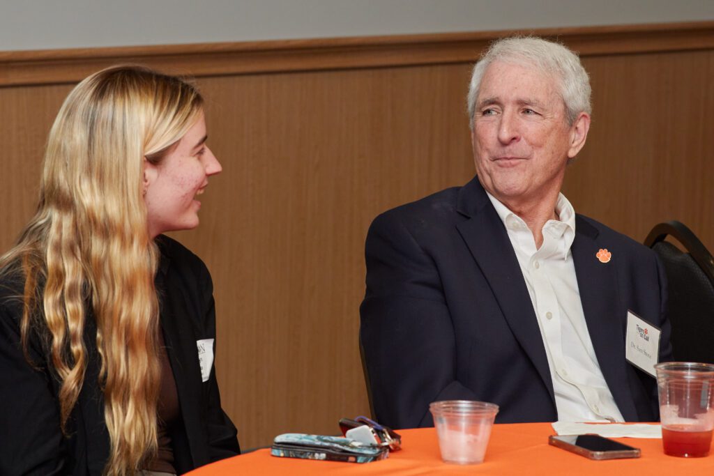 Man (Dr. Sam Stone) and a student sitting at a table at a Tigers on Call event talk to each other.