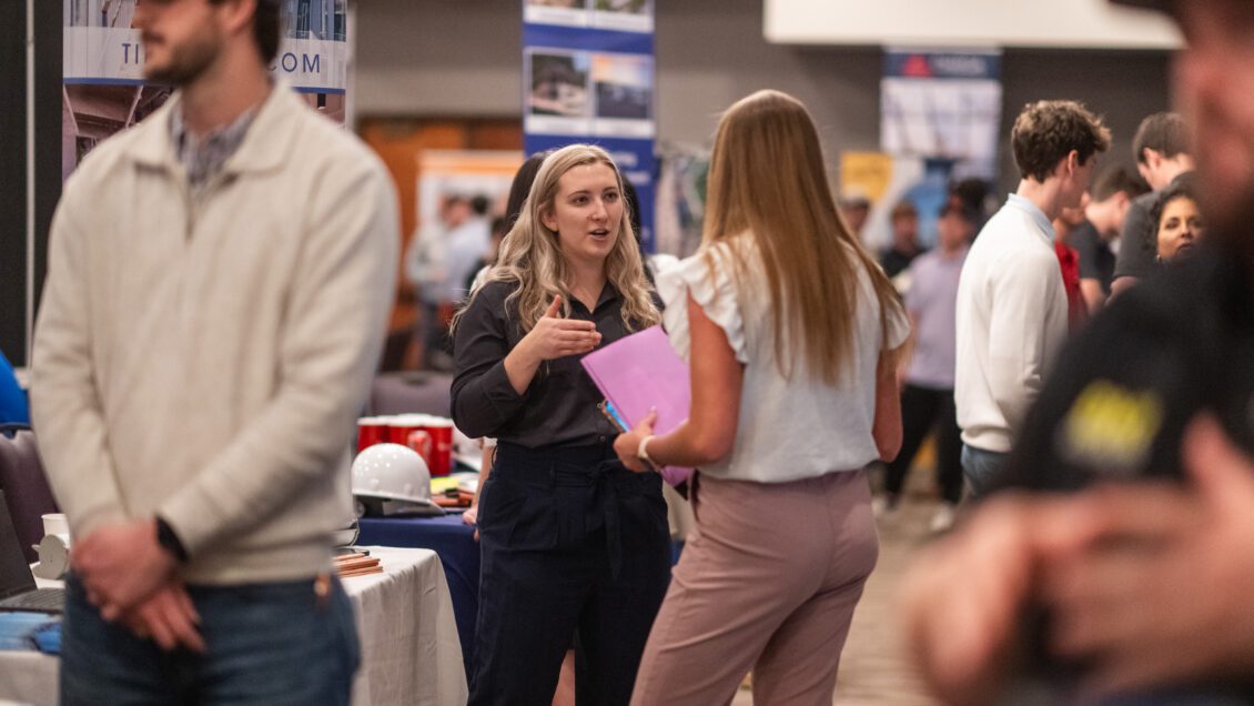A construction science and management student speaks to a recruiter at the Nieri Department of Construction, Development and Planning Career Fair