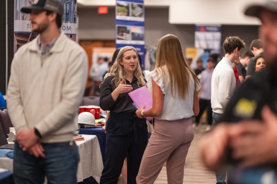 A construction science and management student speaks to a recruiter at the Nieri Department of Construction, Development and Planning Career Fair