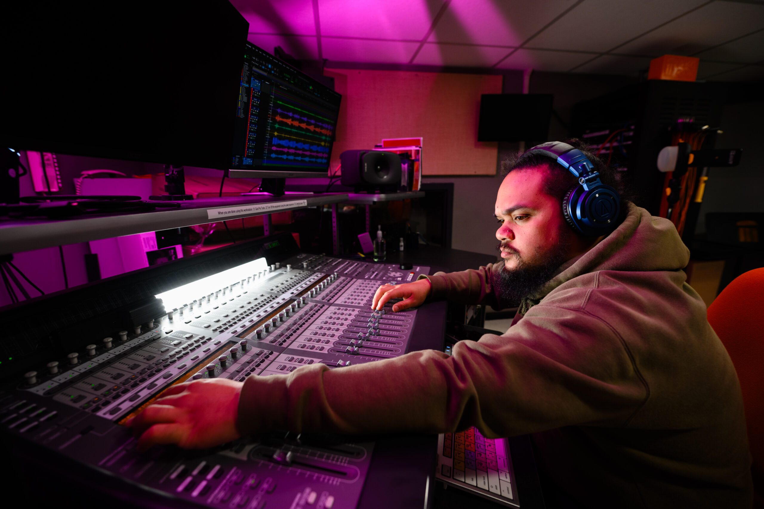 Melvin Villaver works on a mixing board while listening to music on his headphones.