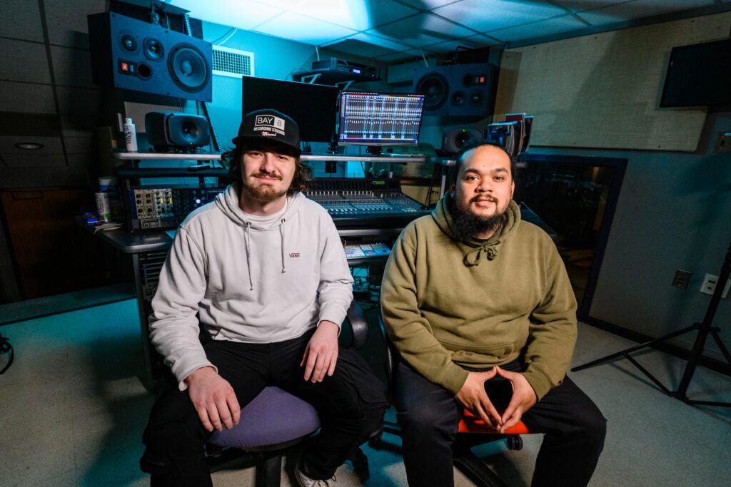TJ Rounds and Melvin Villaver pose for a picture in front of a mixing board in the Brooks Center for the Performing Arts.