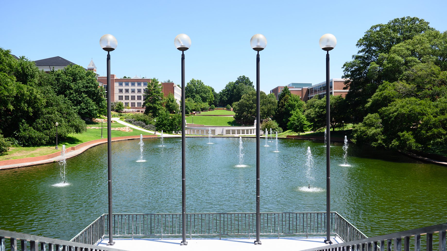 Four lightpoles stand at the bottom of a staircase overlooking the Clemson University reflection pond