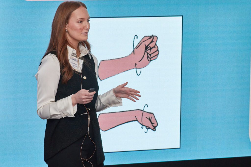 A woman standing in front of a screen that shows two wrists.