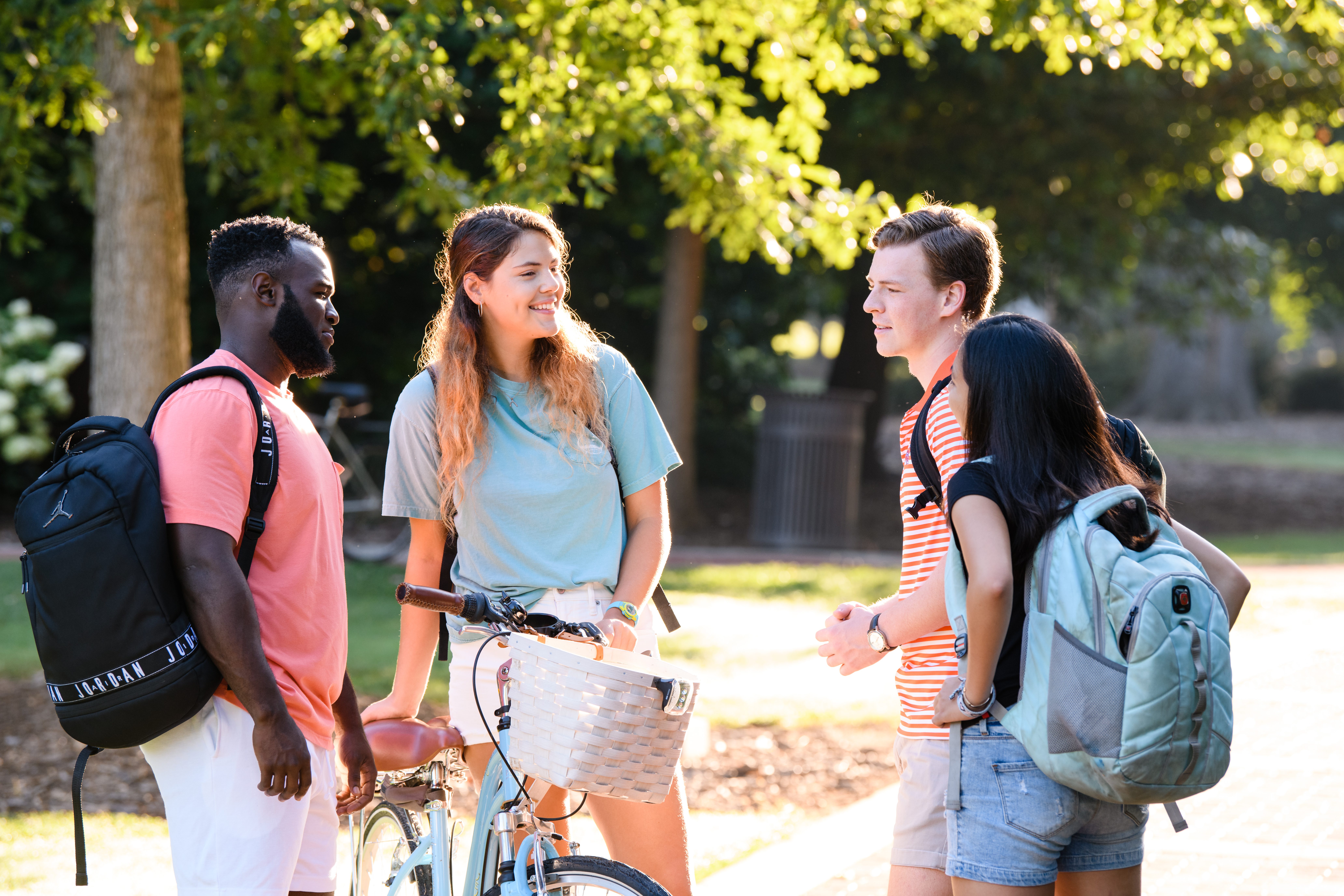 four students gathered around on campus, talking and smiling