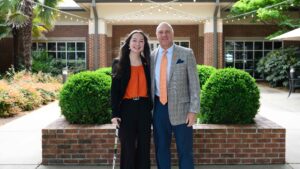 2024 Truman Scholar Elizabeth Caldwell standing and smiling with Clemson University President Jim Clements in front of the Madren Center on campus.
