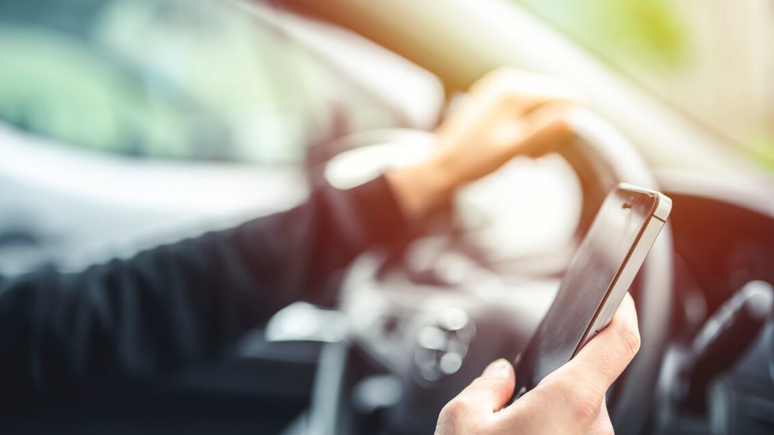 Woman looking at mobile phone while driving a car.