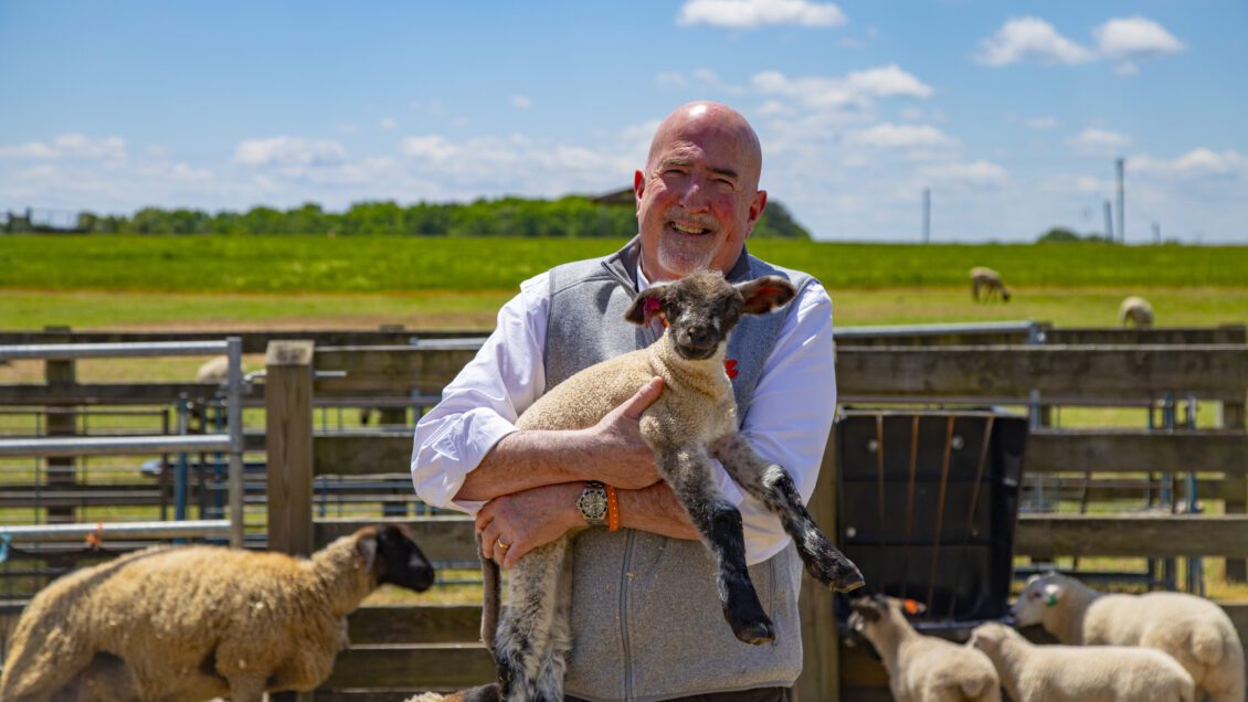 Dean marks posing with lambs.