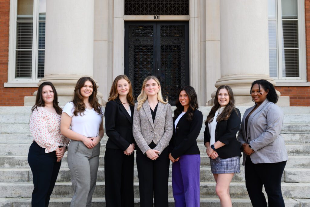 A group of People Advancing Women’s Empowerment members pose for a picture in front of Sikes Hall.