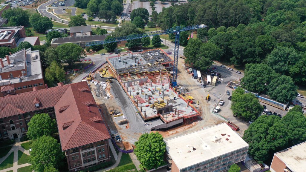 An overhead view of a construction site surrounded by trees and buildings