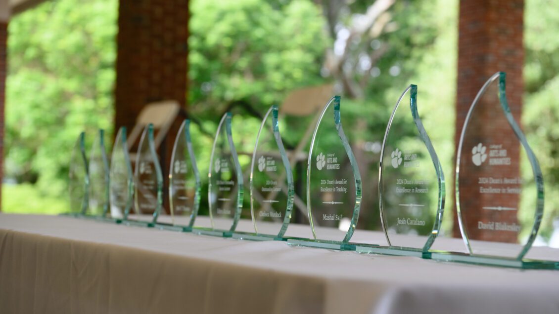 Transparent awards are situated on a tablecloth table.