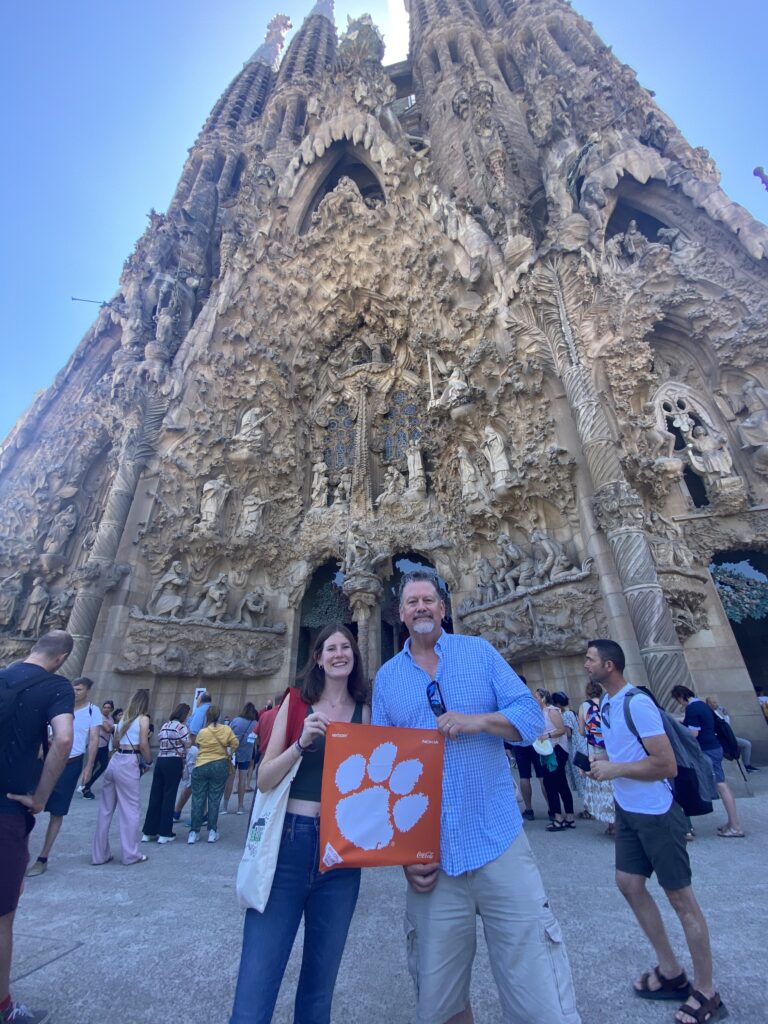 Chris '91 and Helena '24 Harte pose for a picture with a Clemson Tiger Rag in front of the towering La Sagrada Familia in Barcelona, Spain.