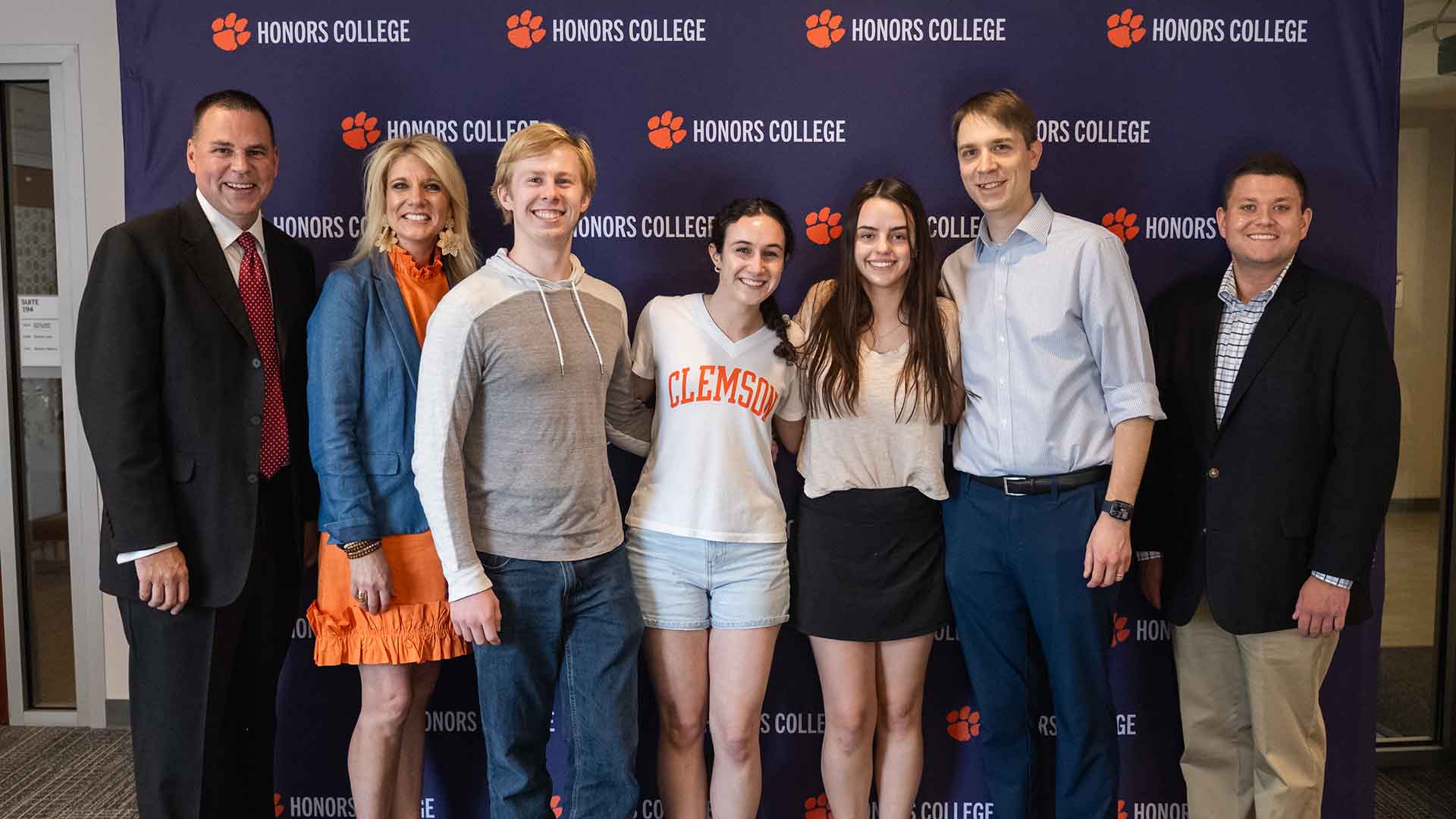 Seven people standing in front of an Honors College backdrop.