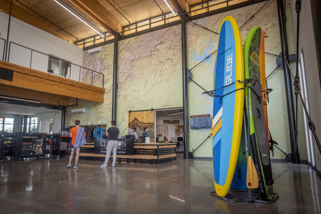 Two people check in at a reception desk with two kayaks nearby. 