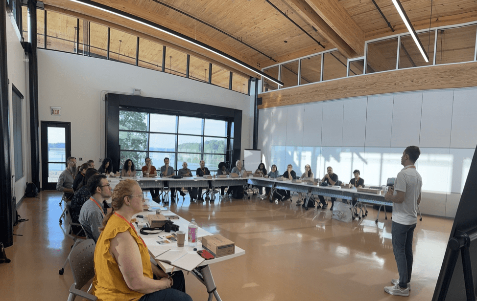 Conference participants sitting at tables listing to a presentation.