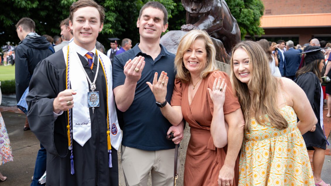 A family of four smile and flash their Clemson rings