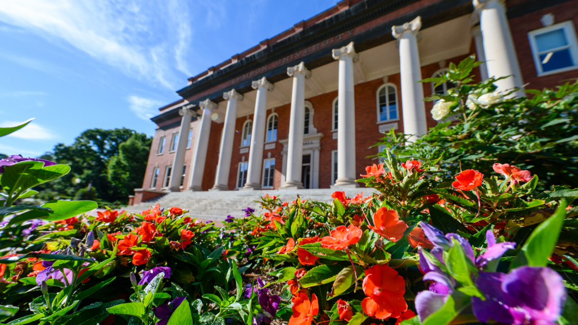 Orange and purple flowers in front of a building with columns.