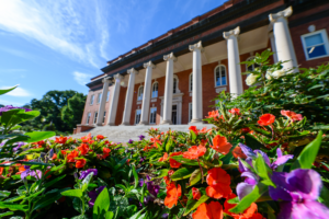 Orange and purple flowers in front of a building with columns.