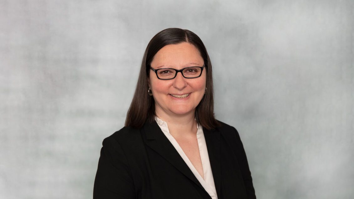 headshot of woman wearing glasses and a black suit