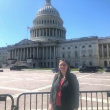 woman wearing a black suit standing in front of the U.S. Capital