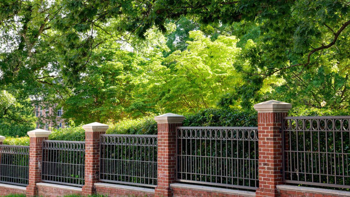 A row of brick pillars in front of trees.