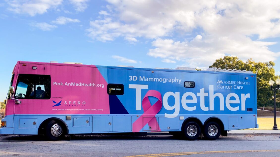 A pink and blue stage coach that reads "Together." parked in front of trees.