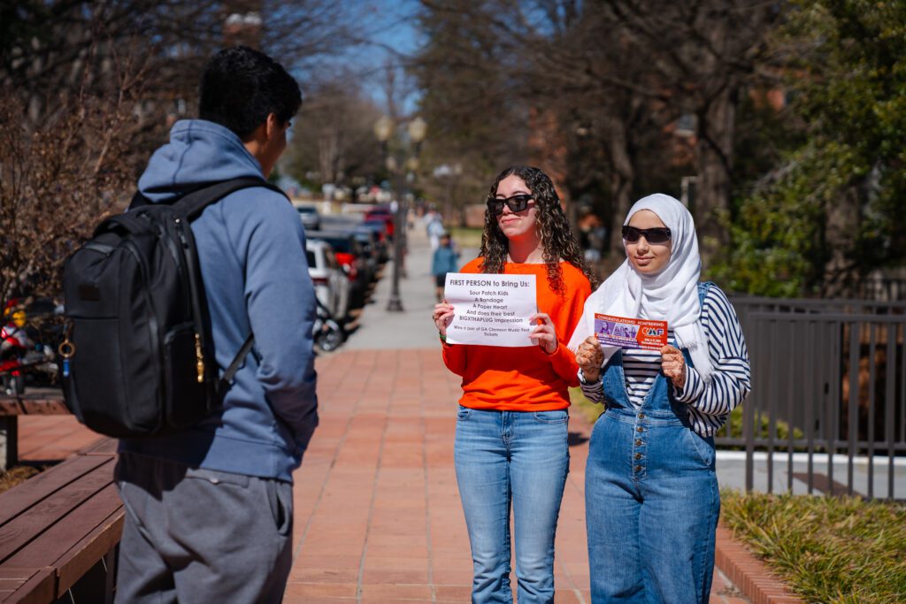 Daniella Lopez and another student conduct a ticket giveaway on campus for Clemson Music Fest 2025