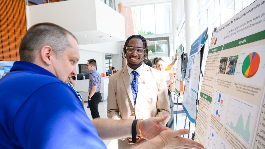 Luther Bells shows off his Creative Inquiry project poster in August 2024