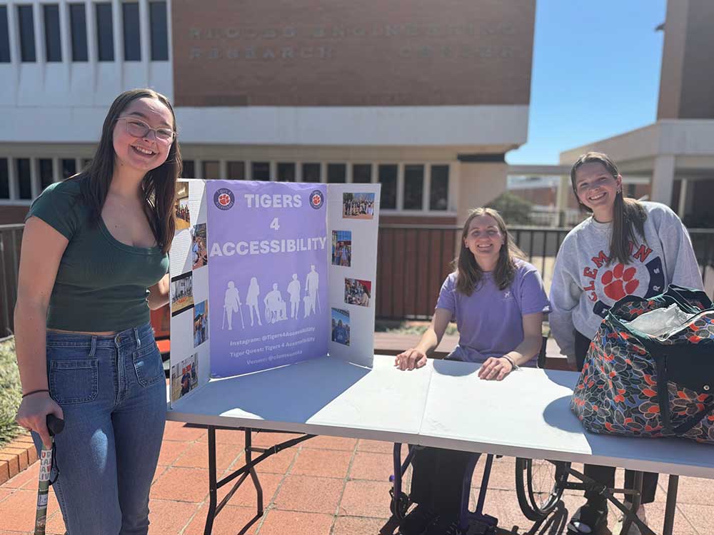 Elizabeth Caldwell with two other students promoting Accessibility Week at a table on Library Bridge.