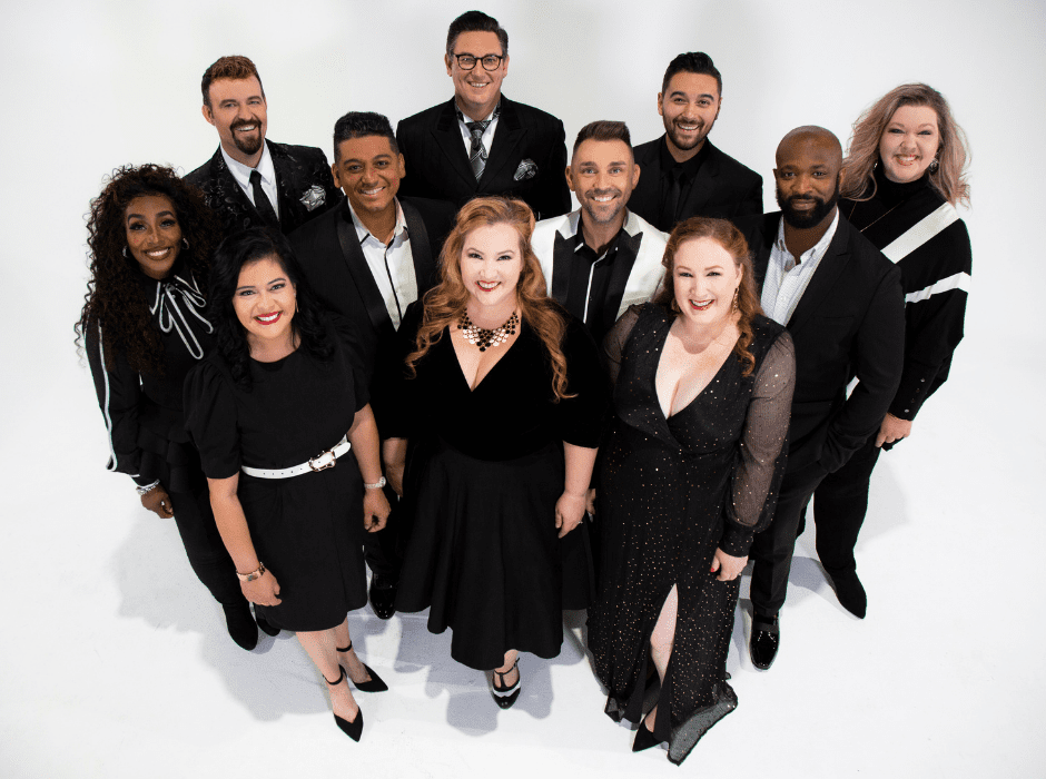 A cappella ensemble Voctave wear black and pose for a portrait in front of a white back drop