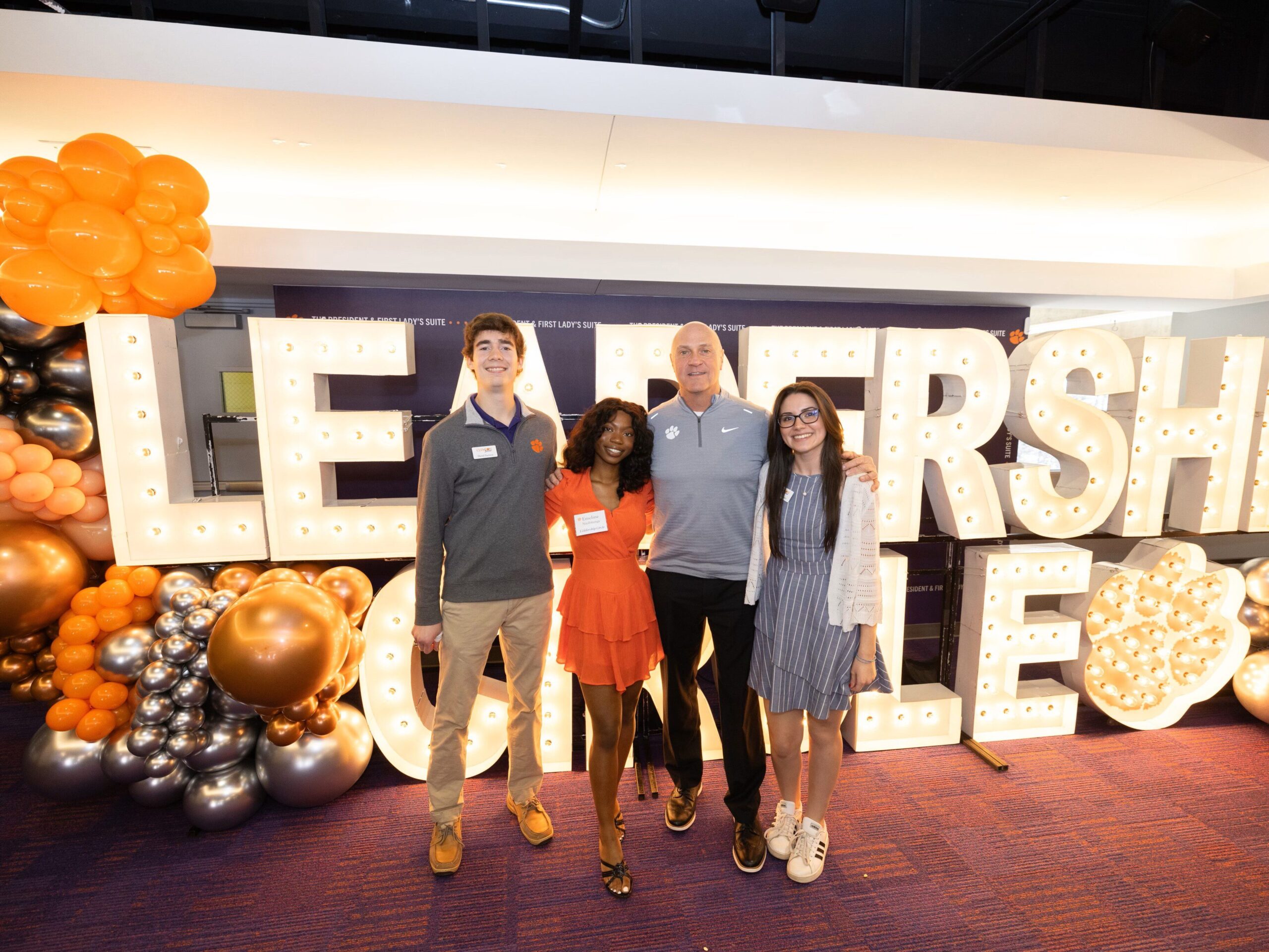 President Clements stands with three students in front of large letters that read "Leadership Circle."