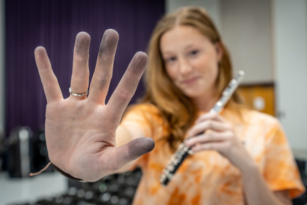 A woman holds her hand to the camera to show her blackened fingertips.