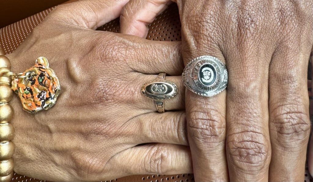 Byars' hand on the right with her Clemson ring, underneath a hand on the left, also with a Clemson ring.