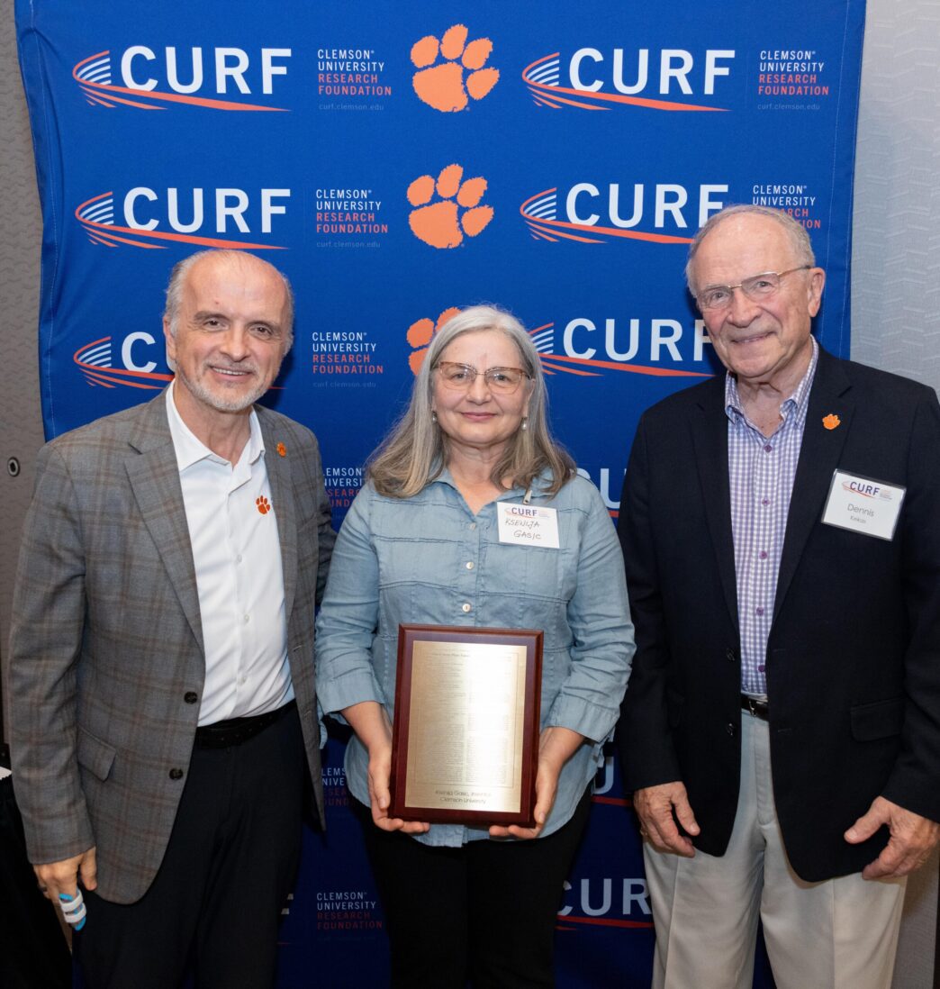 Three people pose for a photo with an award plaque