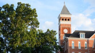 The clock tower of Tillman Hall with trees in the foreground.