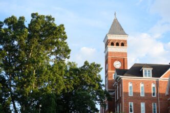 The clock tower of Tillman Hall with trees in the foreground.