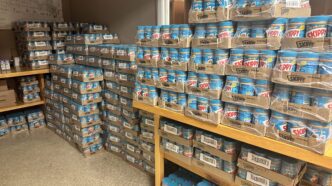 Hundreds of pallets of Skippy peanut butter stacked on the tables and floor in a storage room.