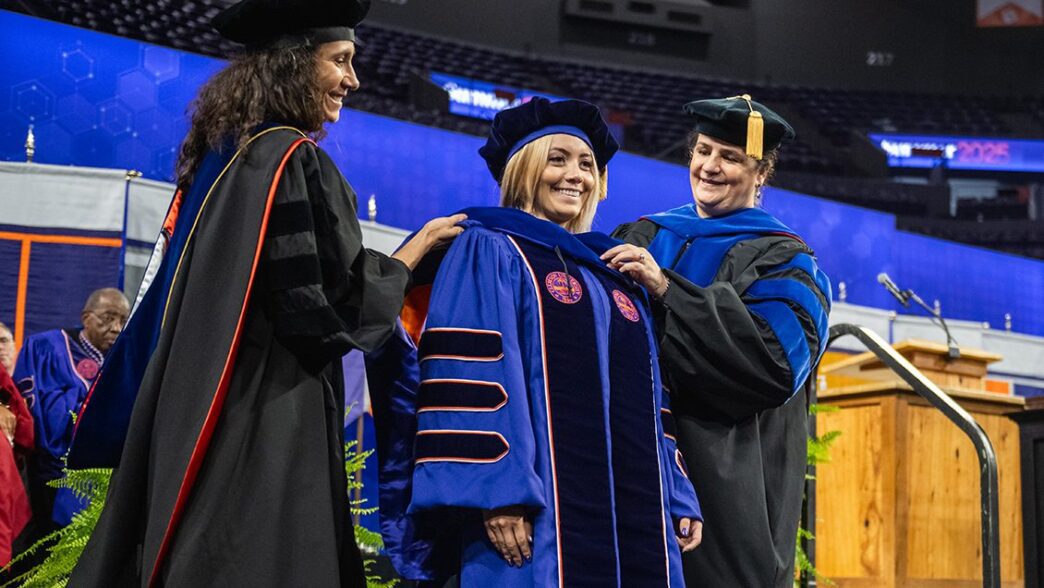 Angelica Solano receives her doctoral hood from her advisor, Shari Rodriguez and CAFLS associate dean for research, Paula Agudelo