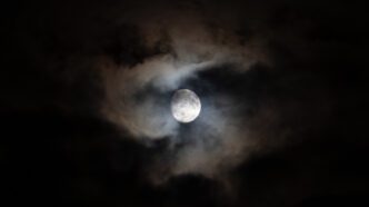 A waxing gibbous moon with some clouds.
