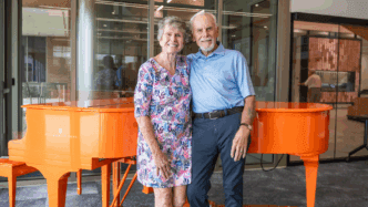 Bill and Donna Eskridge pose in front of the Clemson Orange Steinway Piano
