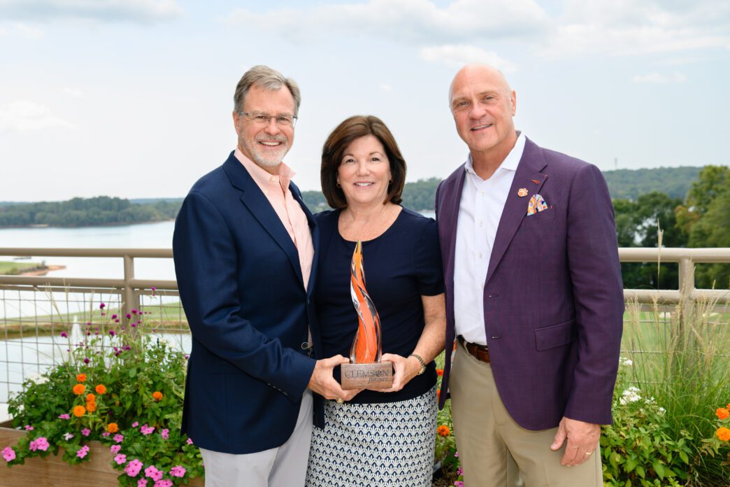 President Clements stands with Brad and Lyle Smith on the roof top terrace of the Nieri Family Alumni and Visitors Center with Lake Hartwell behind them.