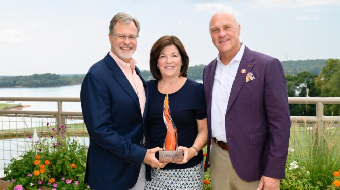 President Clements stands with Brad and Lyle Smith on the roof top terrace of the Nieri Family Alumni and Visitors Center with Lake Hartwell behind them.