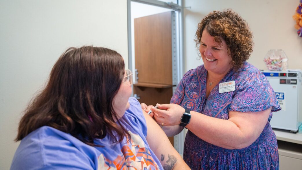 a friendly pharmacist administers a vaccine to a student in a clinical office setting