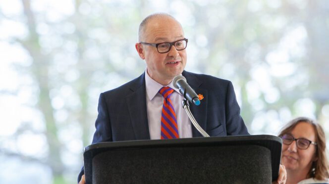 Nicholas Vazsonyi, Dean of the College of Arts and Humanities, speaks at a podium outdoors