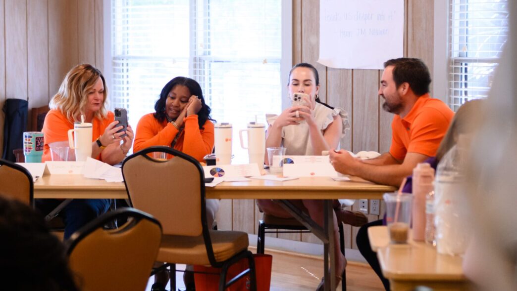 Staff members sit around a table at a retreat on campus