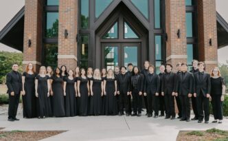 a group of students dressed in black pose for a photo in front of a chapel