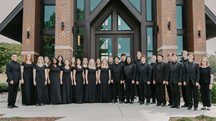 a group of students dressed in black pose for a photo in front of a chapel